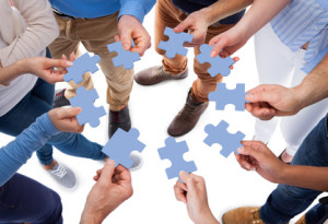 High angle view of people connecting puzzle pieces over white background